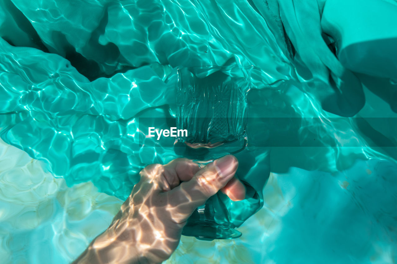Cropped hands of woman holding prism in swimming pool