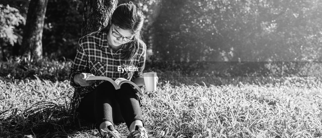Woman reading book while sitting in park