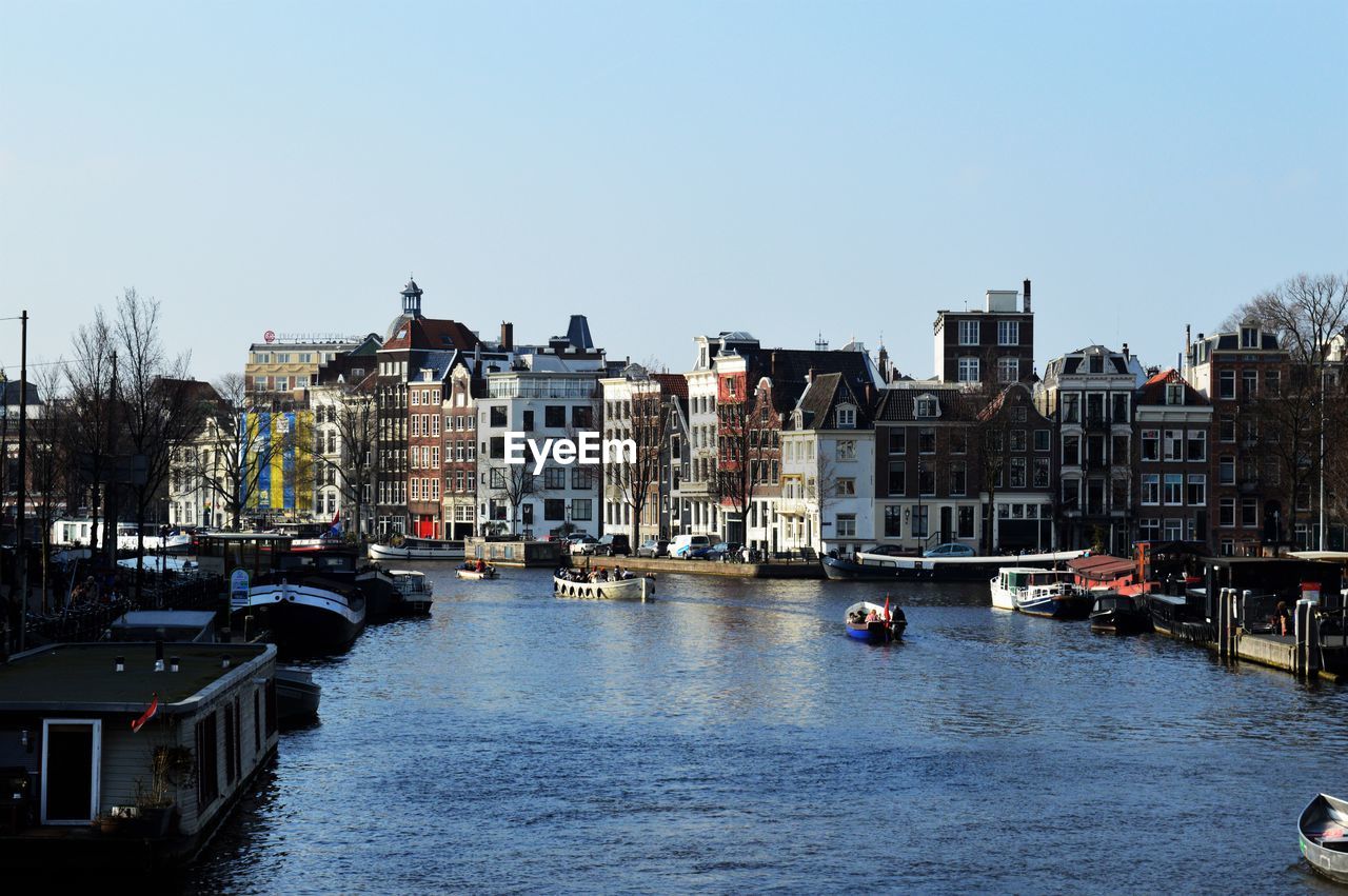 Canal amidst buildings in city against clear sky