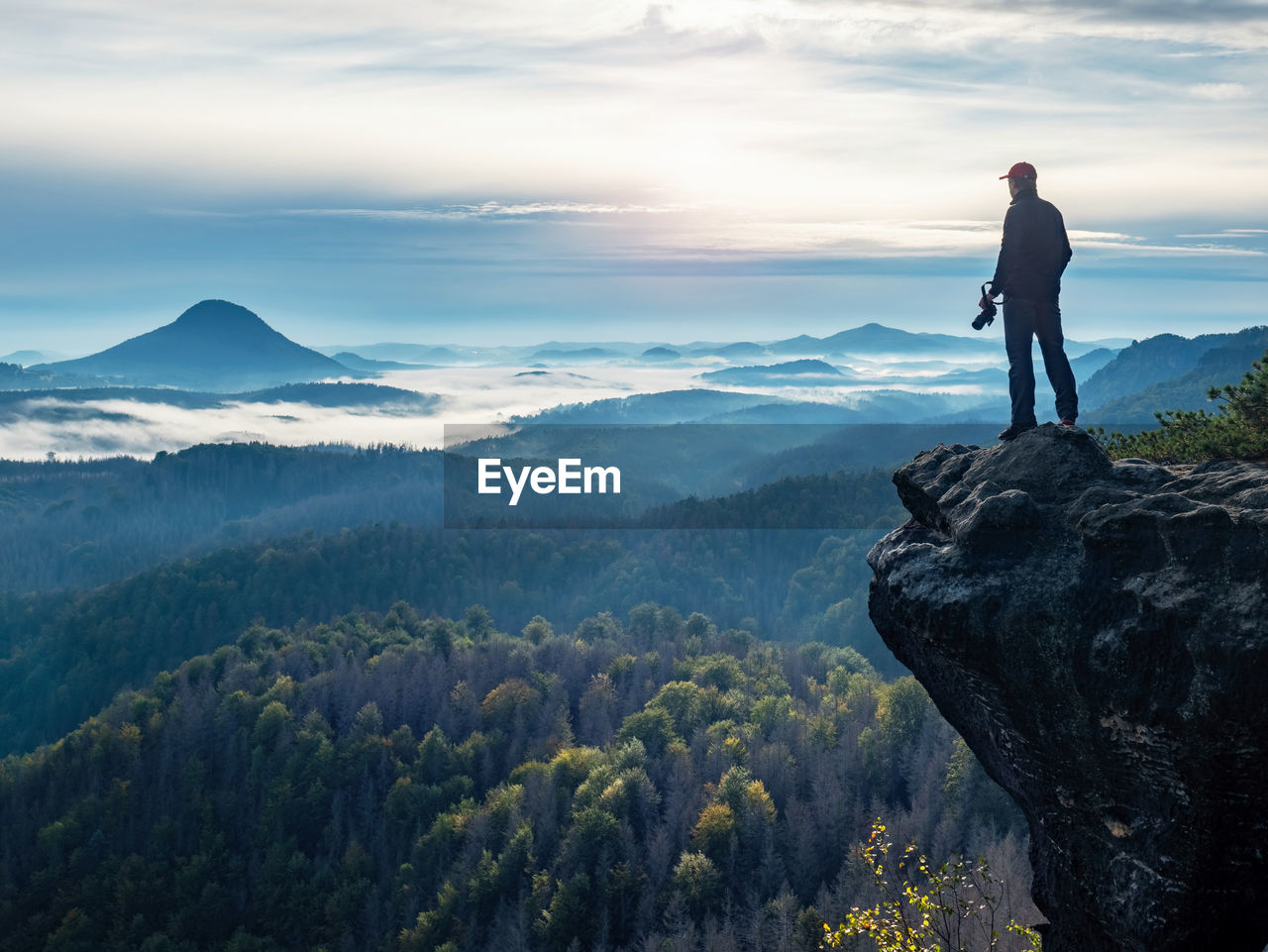 Photographer looking with camera in hands for subject bellow mountain path. discovery travel concept