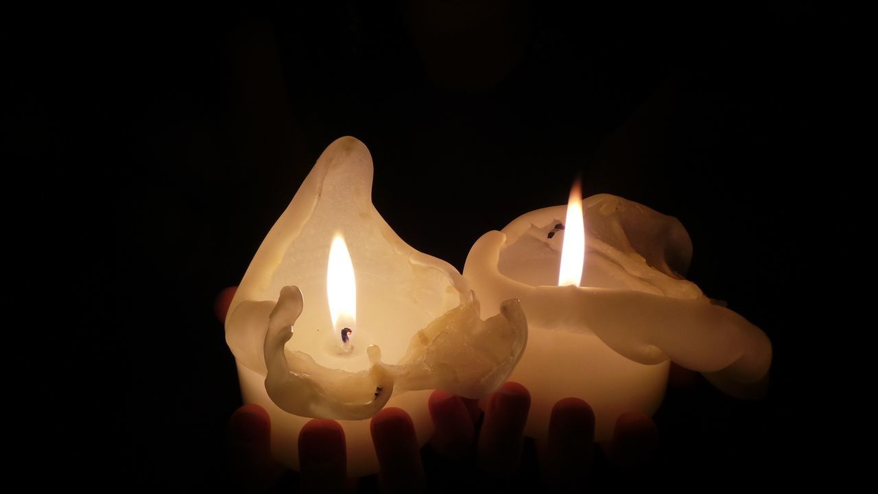 Close-up of lit candles over black background