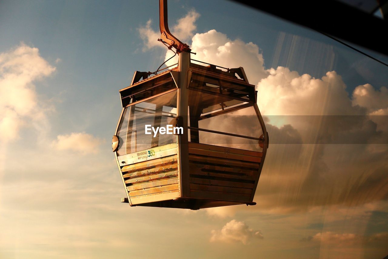 Low angle view of overhead cable car against sky seen through glass window