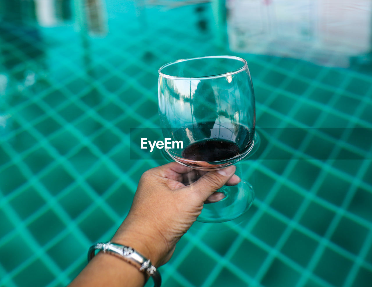 Cropped image of man drinking glass in swimming pool