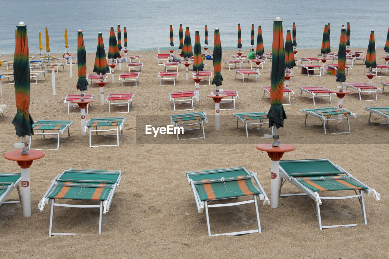EMPTY CHAIRS AND TABLES ON BEACH