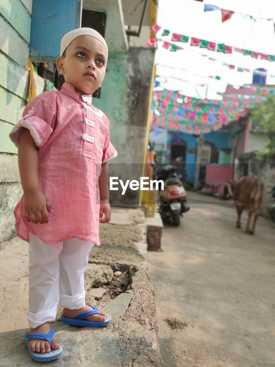 Full length of cute boy standing on footpath wearing religious dress 