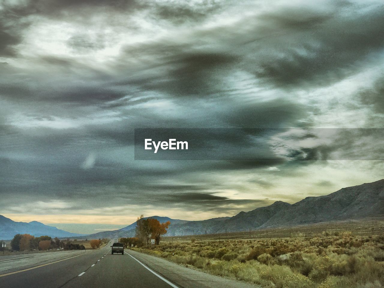 ROAD BY STORM CLOUDS OVER LANDSCAPE