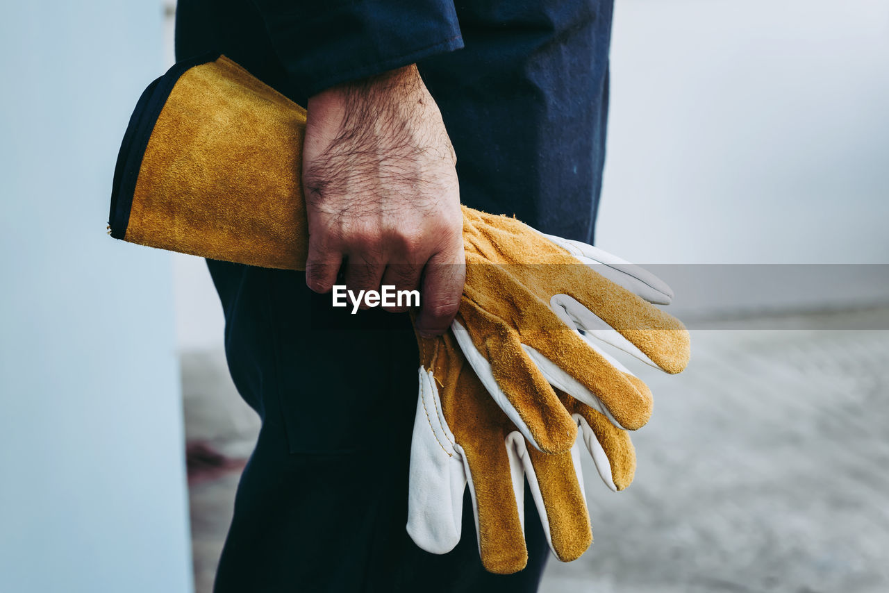 Close-up of man holding gloves at industry