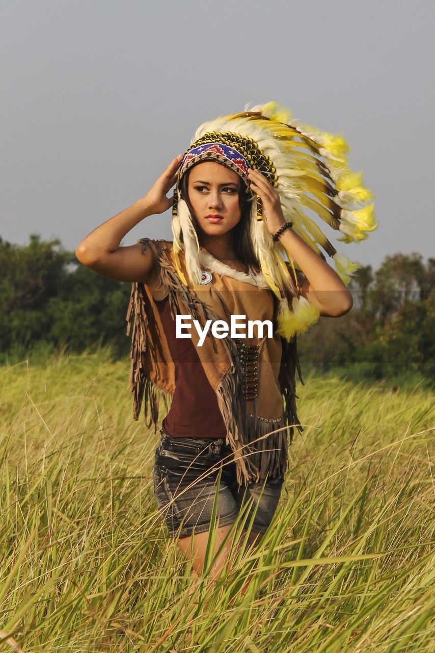 Young woman looking away while wearing headdress on field