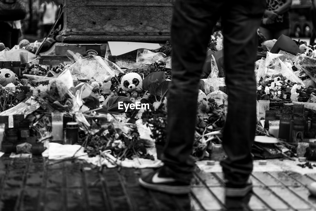 Low section of man standing by flowers at cemetery