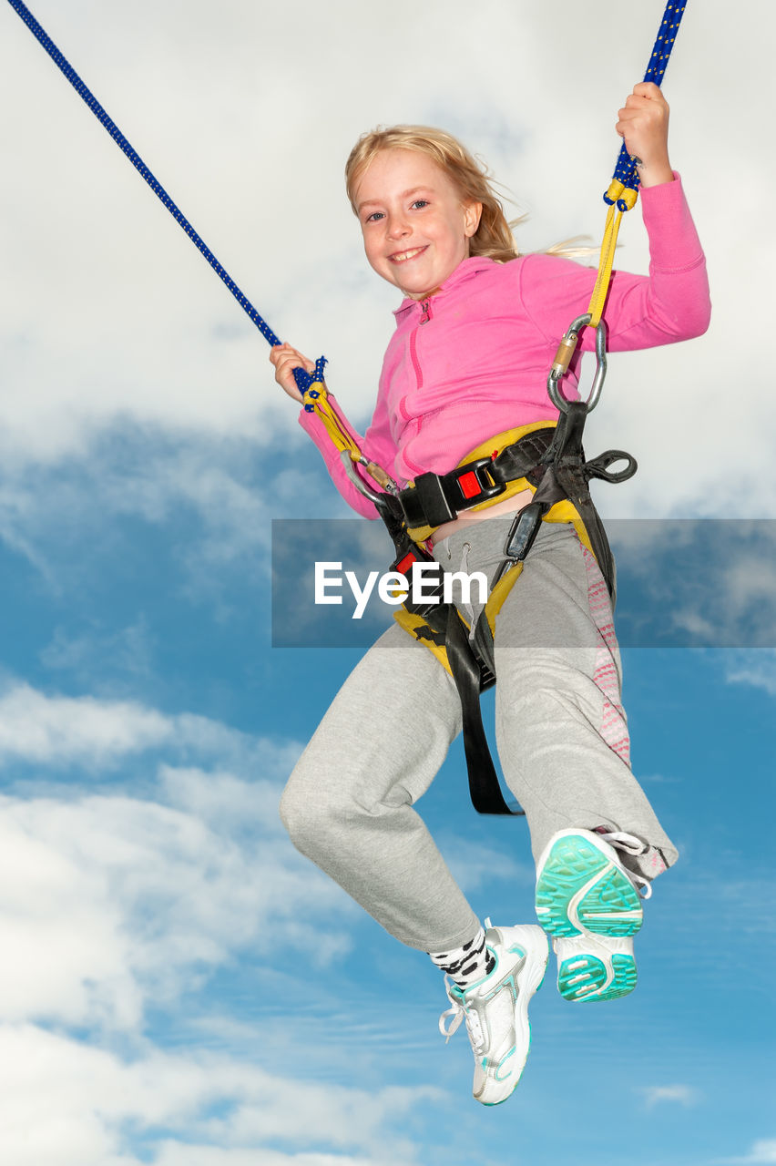 Low angle view of woman holding rope against sky