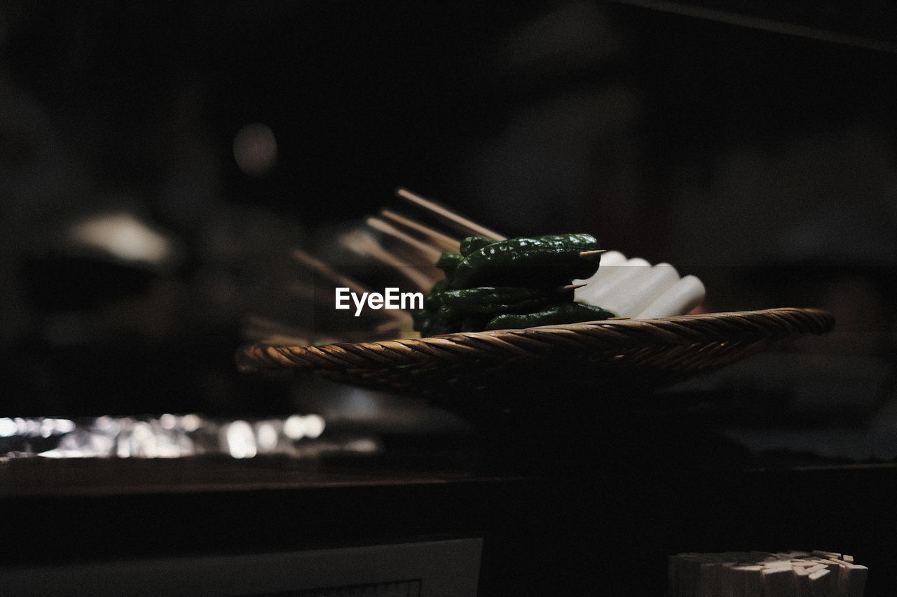 Close-up of food on wicker basket in darkroom
