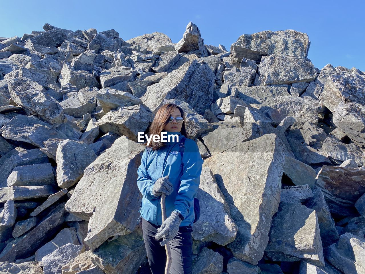 Woman standing on rock against blue sky