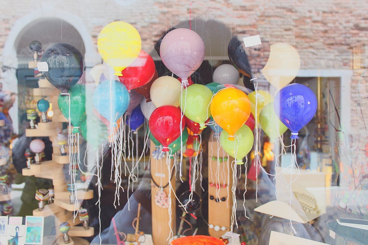 Colorful balloons in store seen through glass