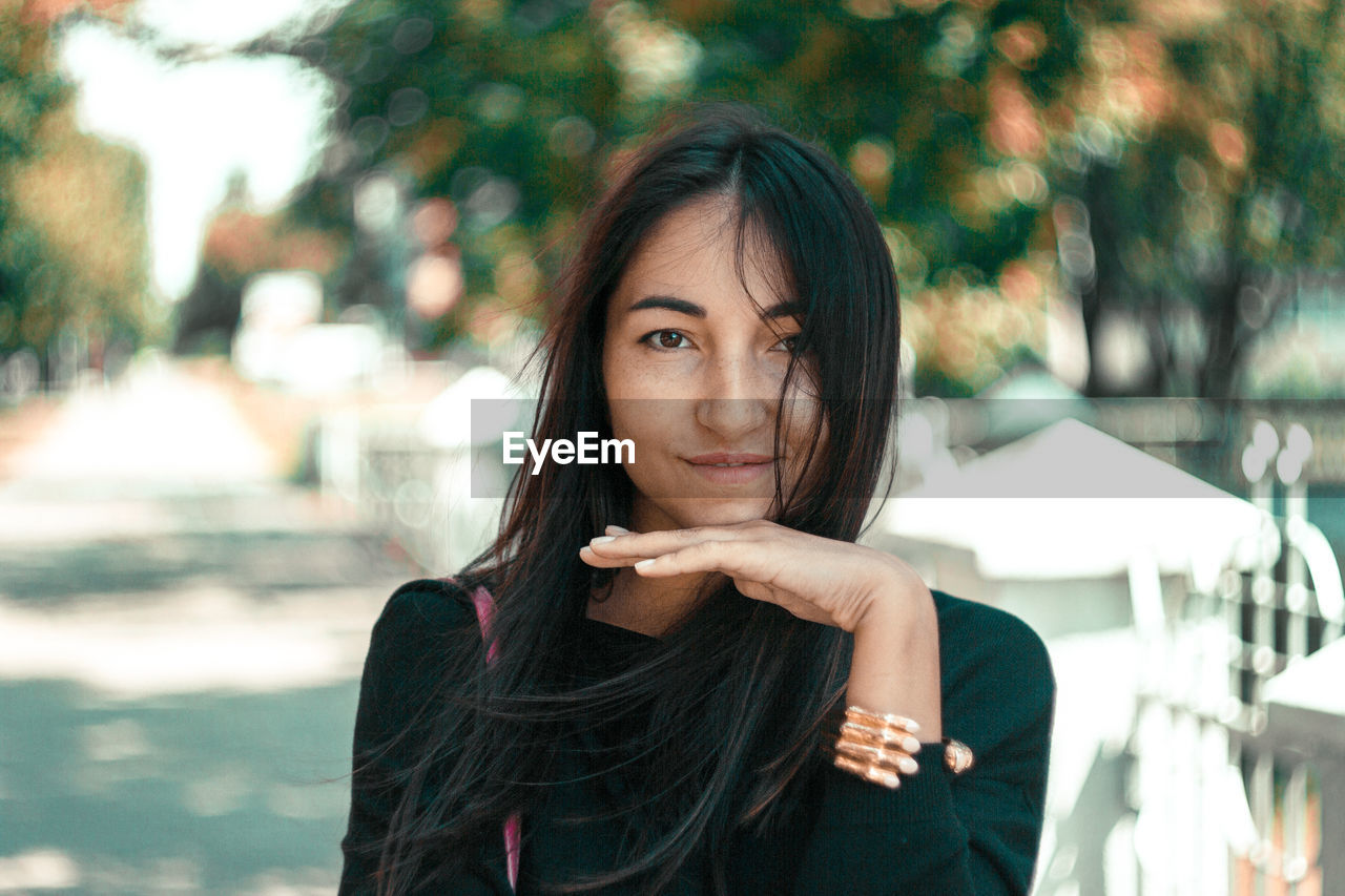 Portrait of young woman with long hair standing outdoors