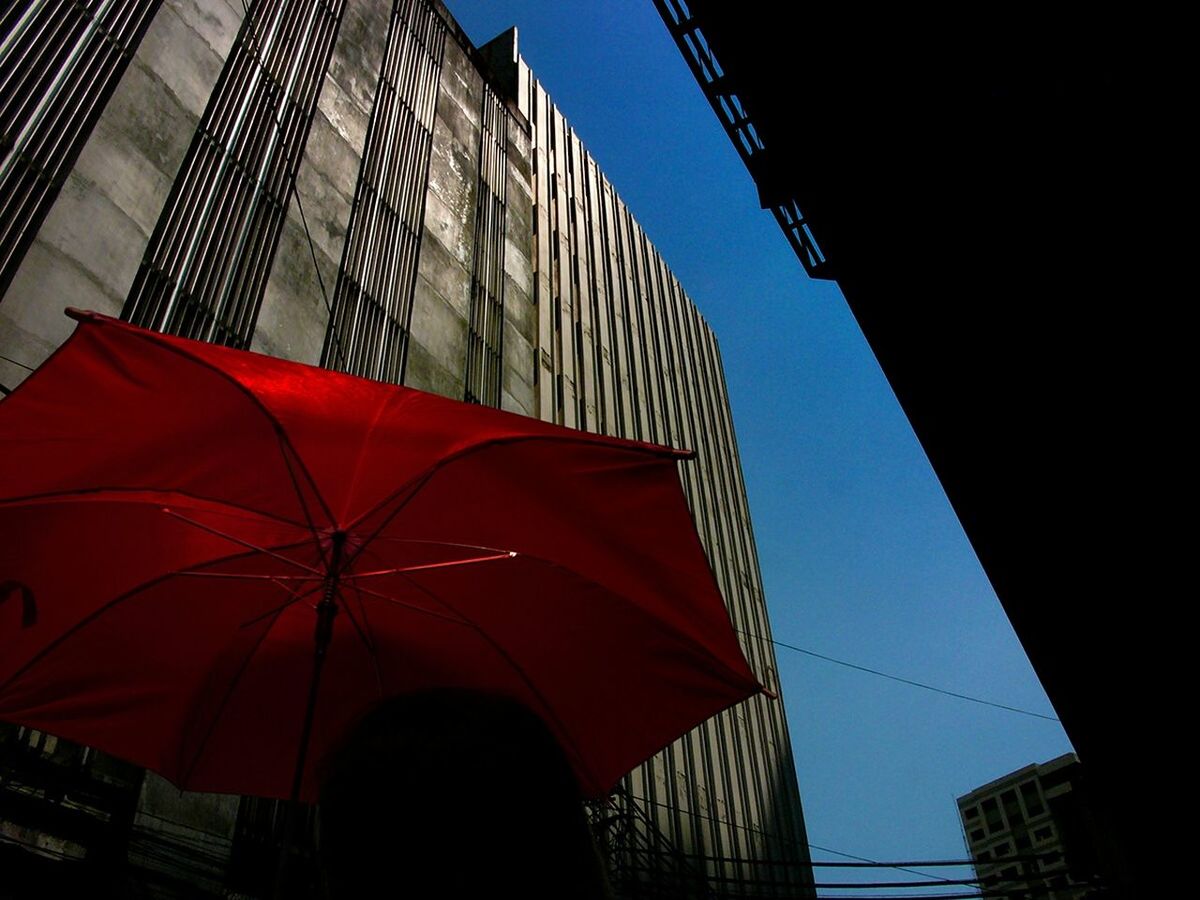 Low angle view of umbrella and skyscrapers against clear sky
