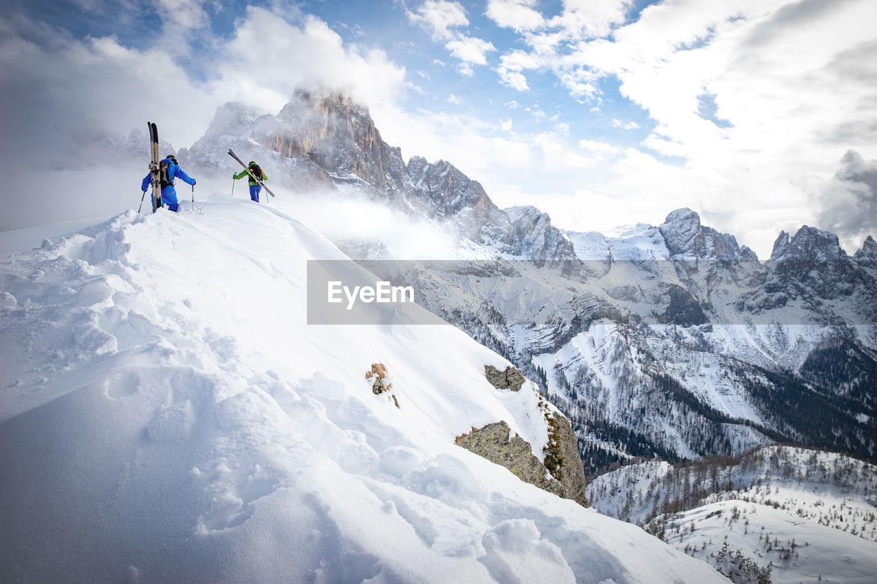 People hiking on snowcapped mountain during winter