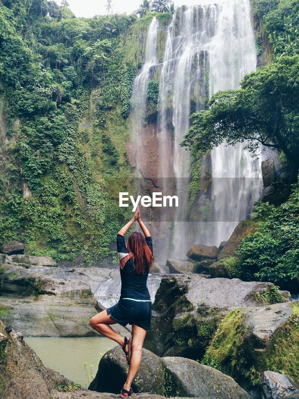 Full length of woman exercising near waterfall