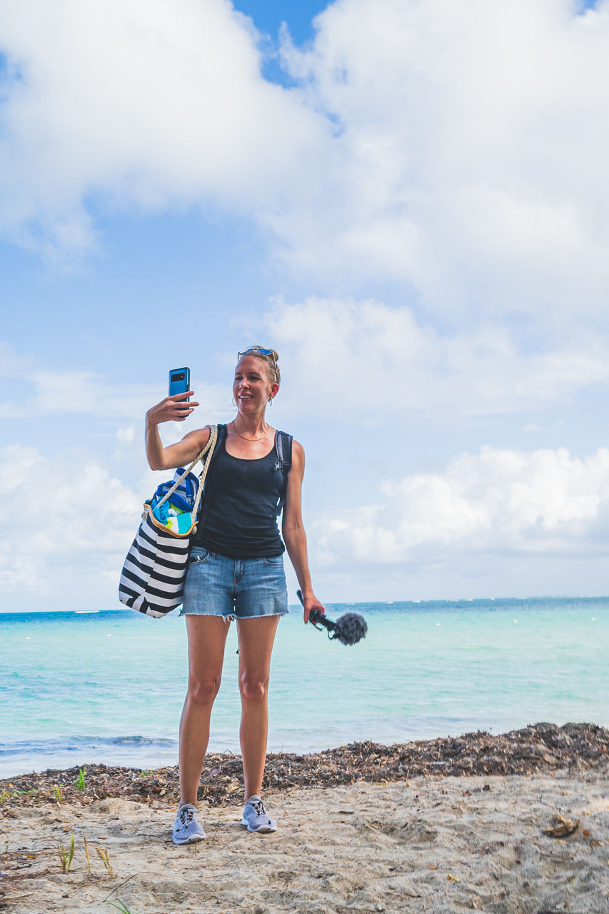 full length of woman exercising at beach