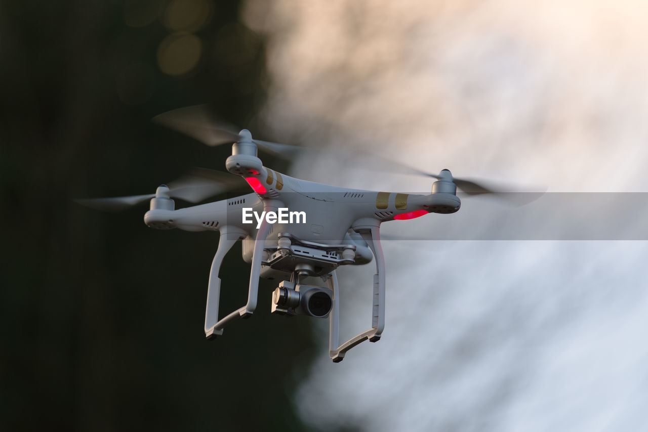 Remote control quadcopter camera drone flying in the evening sky. plain background and motion blur