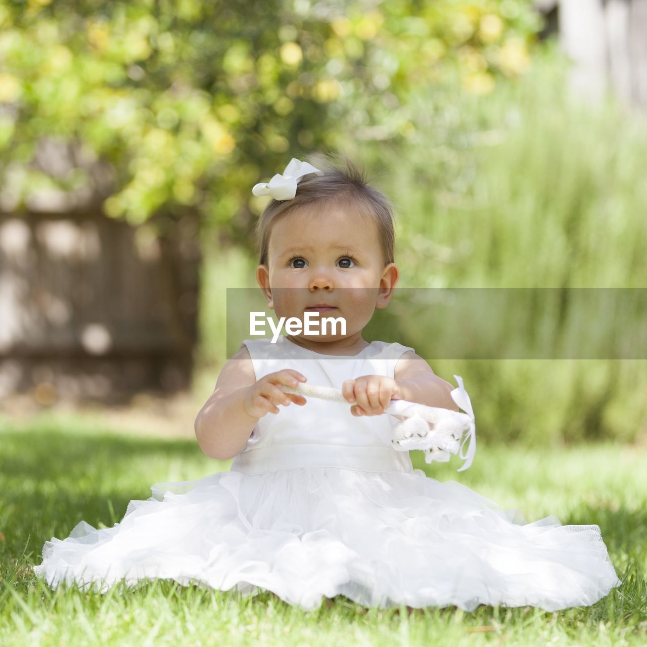 Cute baby girl looking away while sitting on grass
