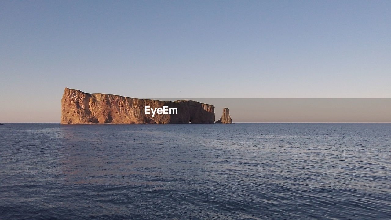 ROCK FORMATIONS BY SEA AGAINST CLEAR SKY
