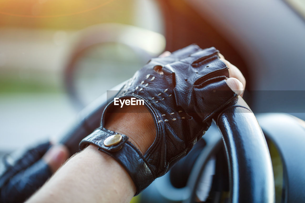 The driver's hands in leather gloves driving a moving car. woman holding