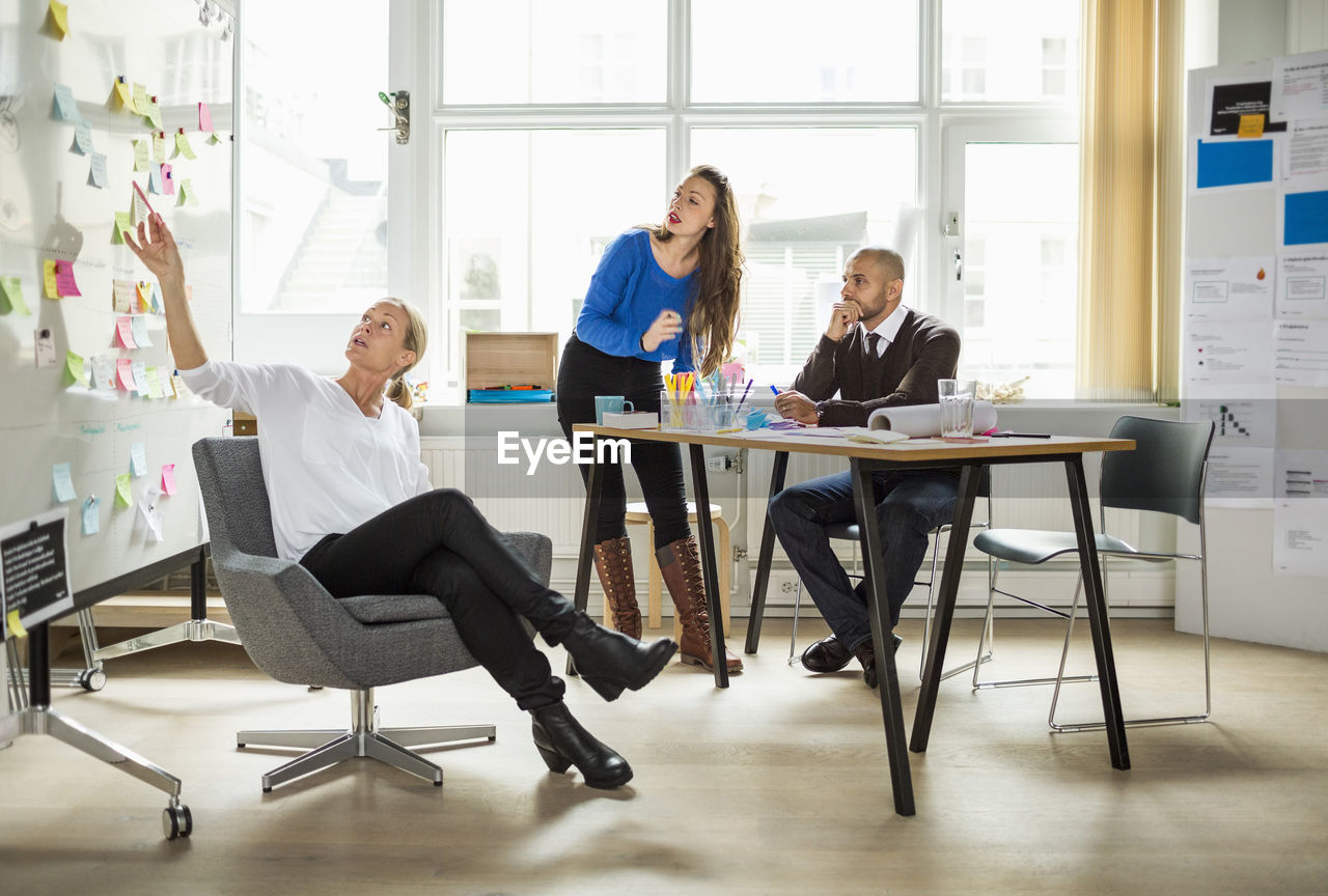 Business people discussing over adhesive note in creative office