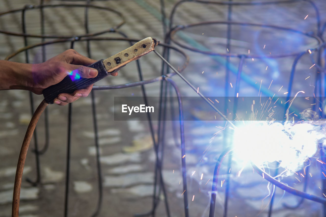 Cropped hand of man welding outdoors