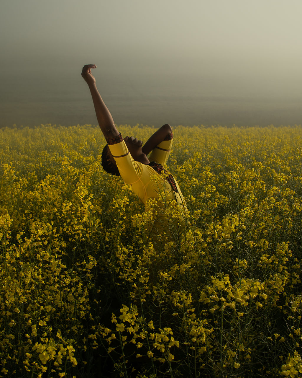 Young man standing amidst yellow flowers on oilseed rape landscape