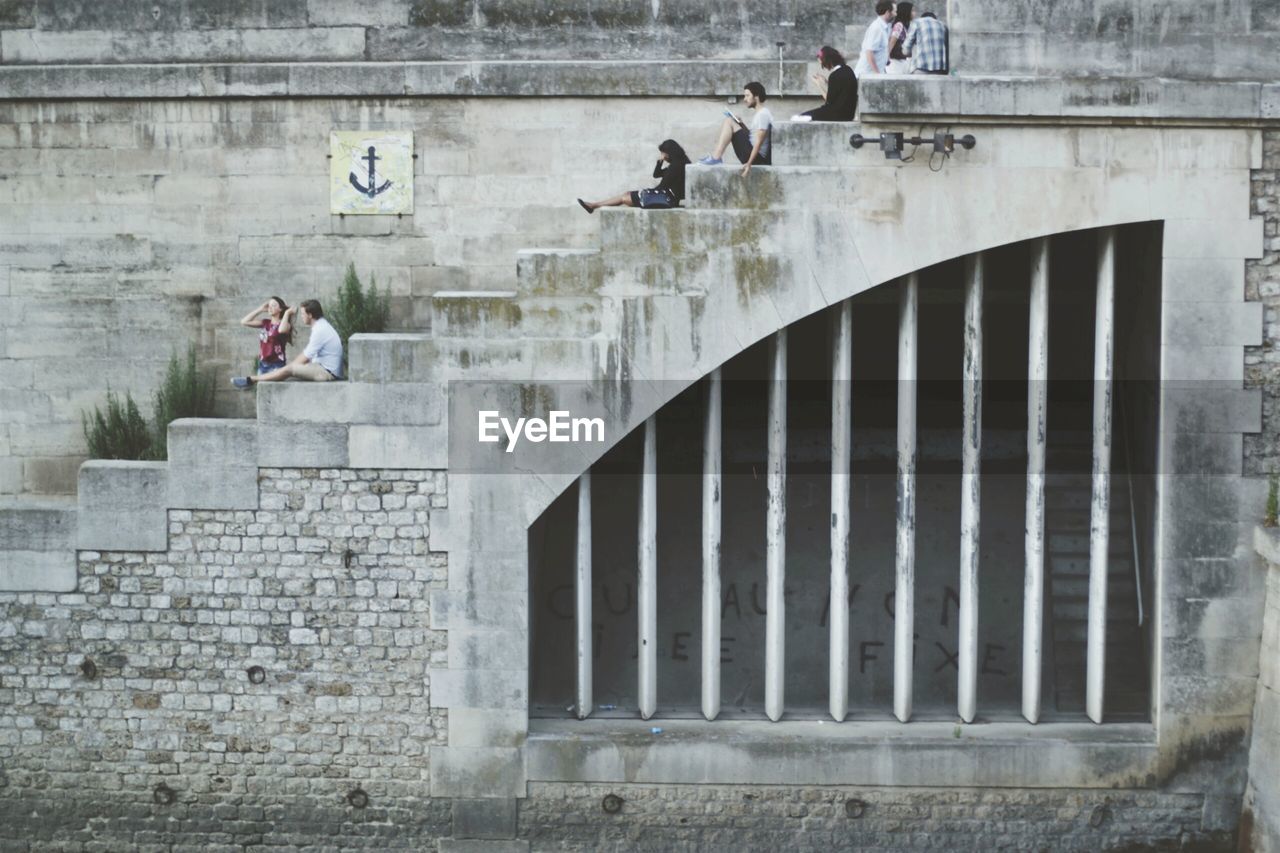 People sitting on steps at river embankment