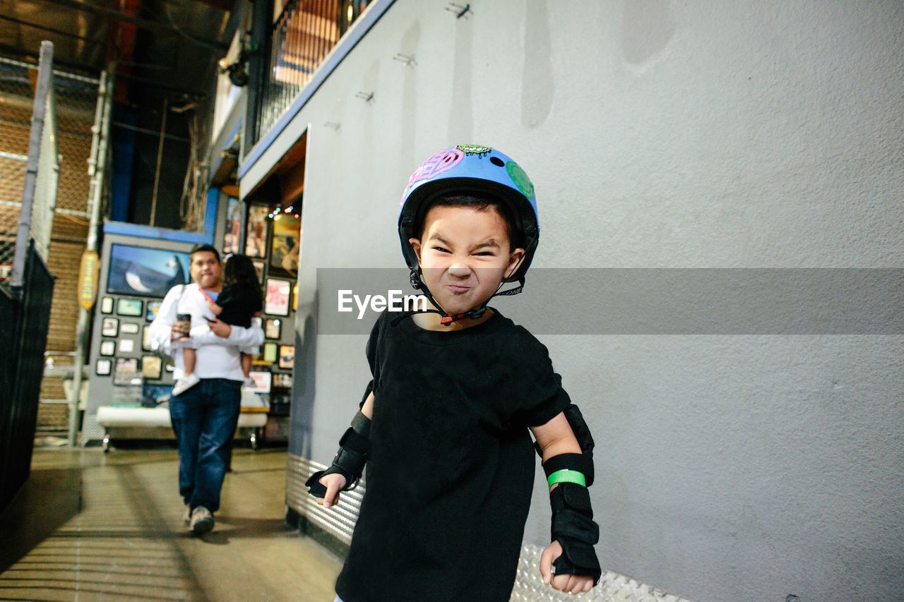 A young boy wearing a helmet makes a silly face for the camera