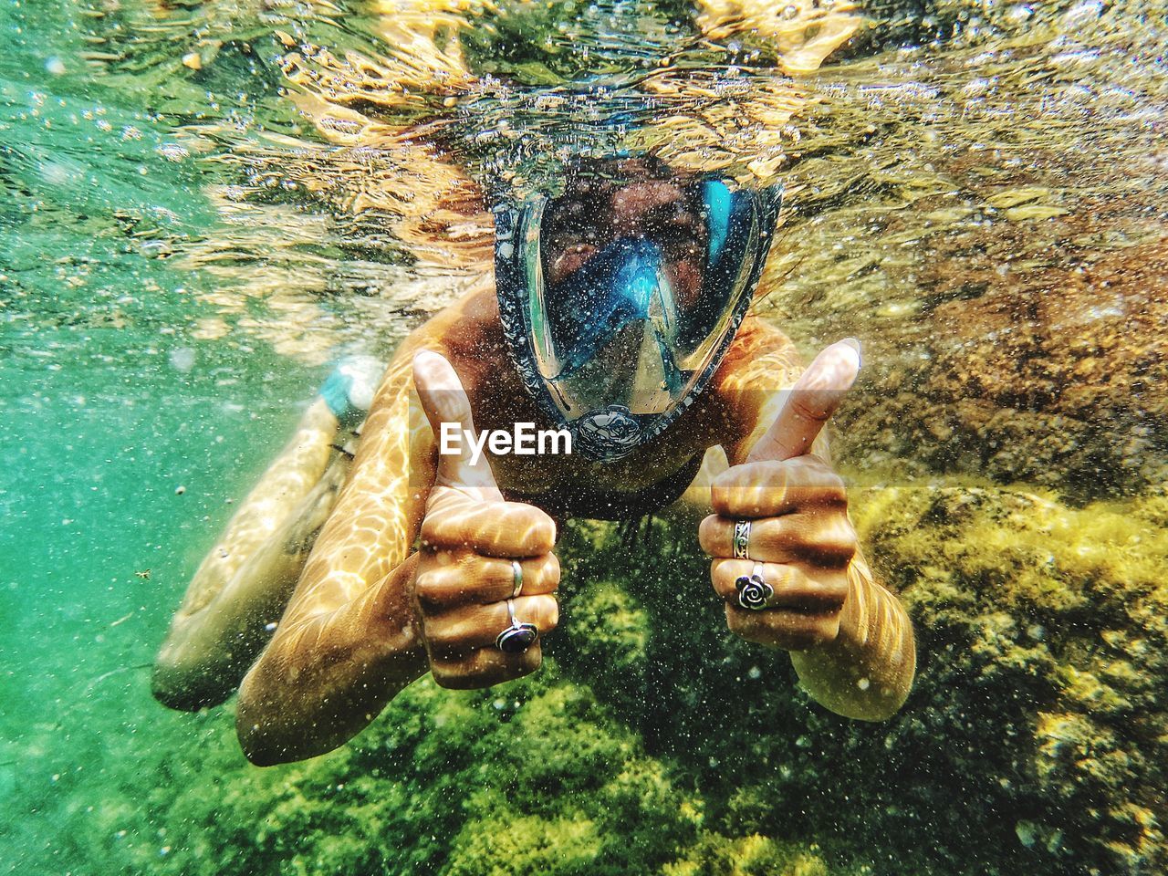 Portrait of woman showing thumbs up while swimming in undersea