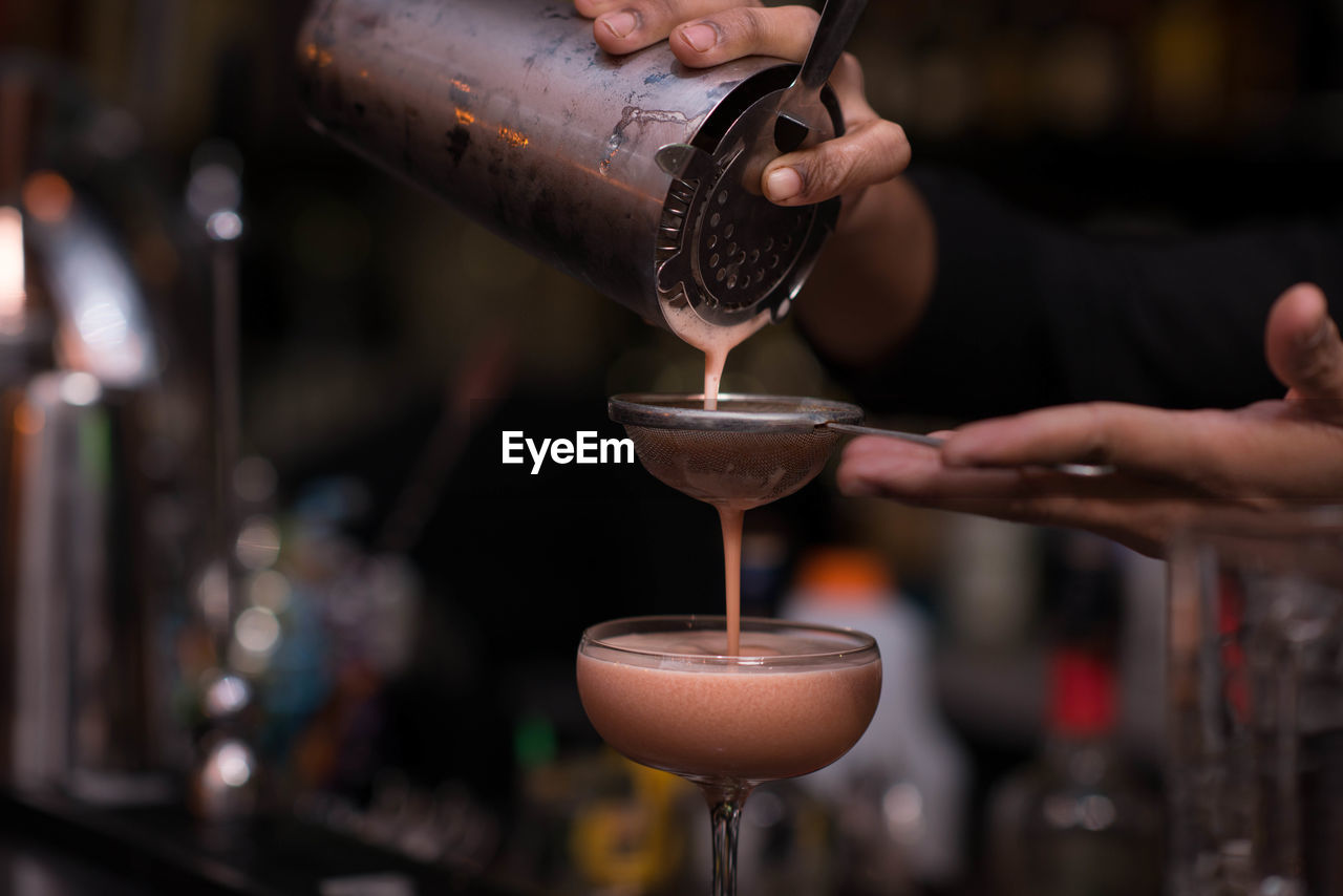 Close-up of bartender pouring cocktail