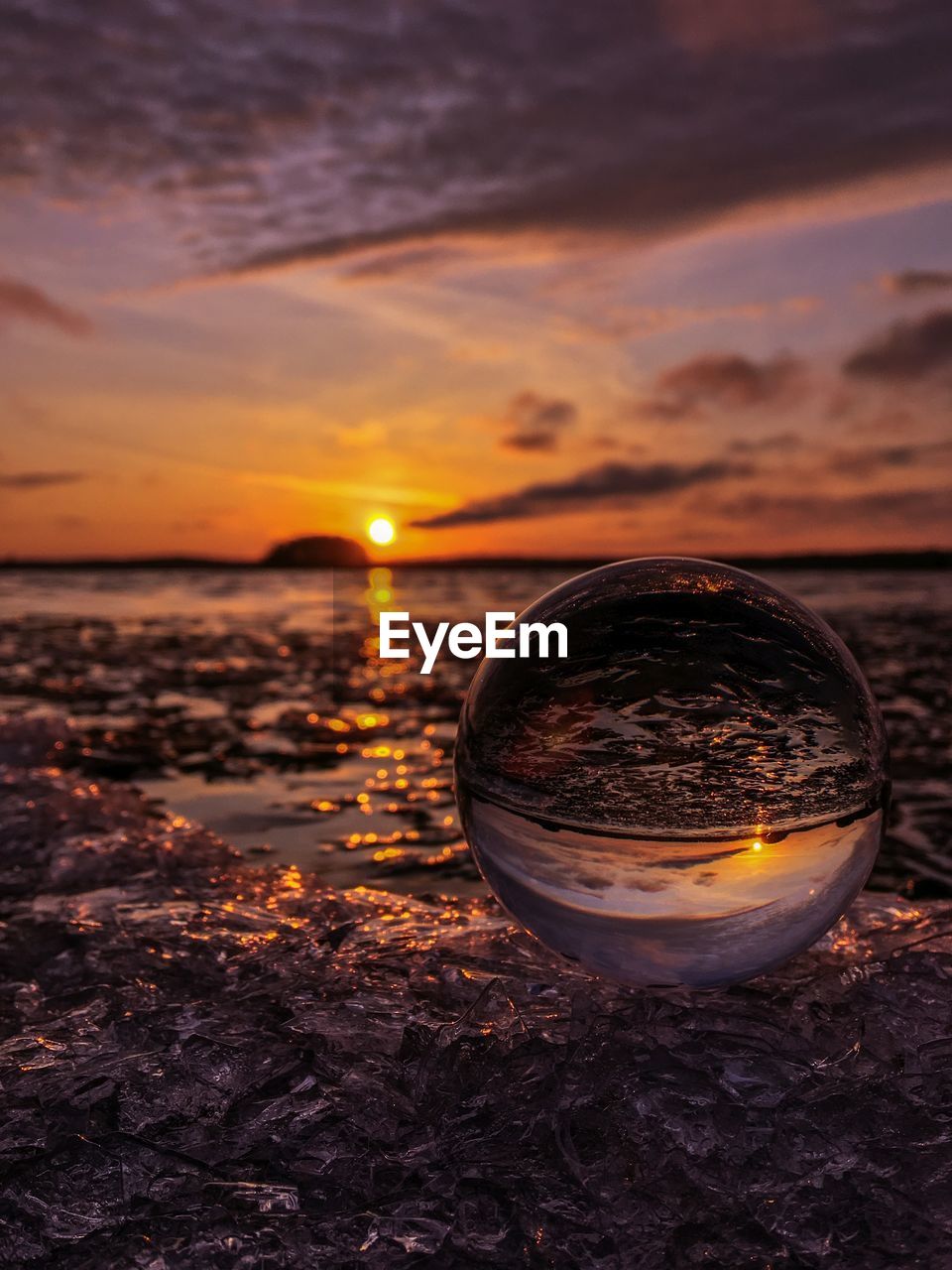 Glass on beach against sky during sunset