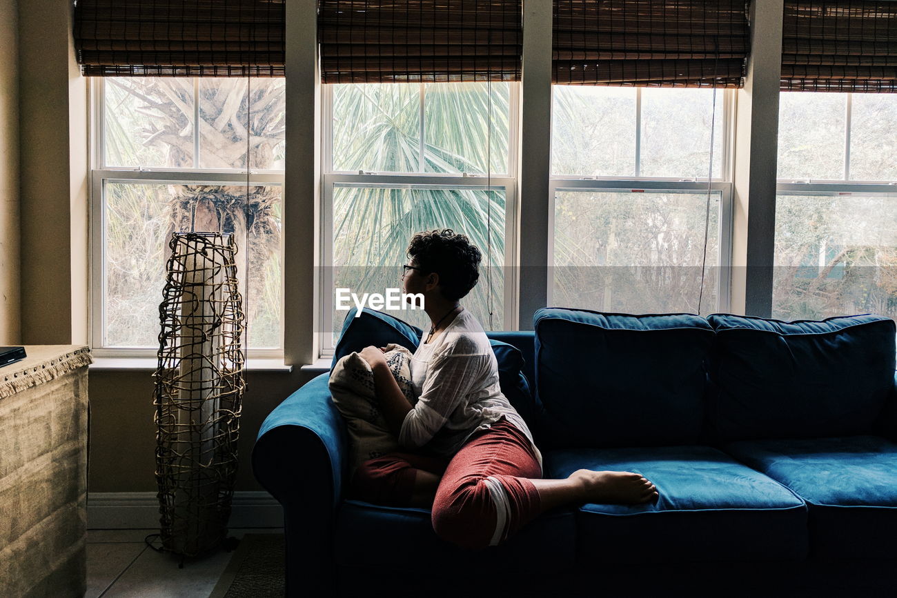 Teenage Girl Sitting On Sofa By Window At Id 120804830