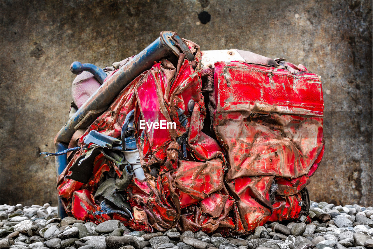 Close-up of crushed red car at junkyard