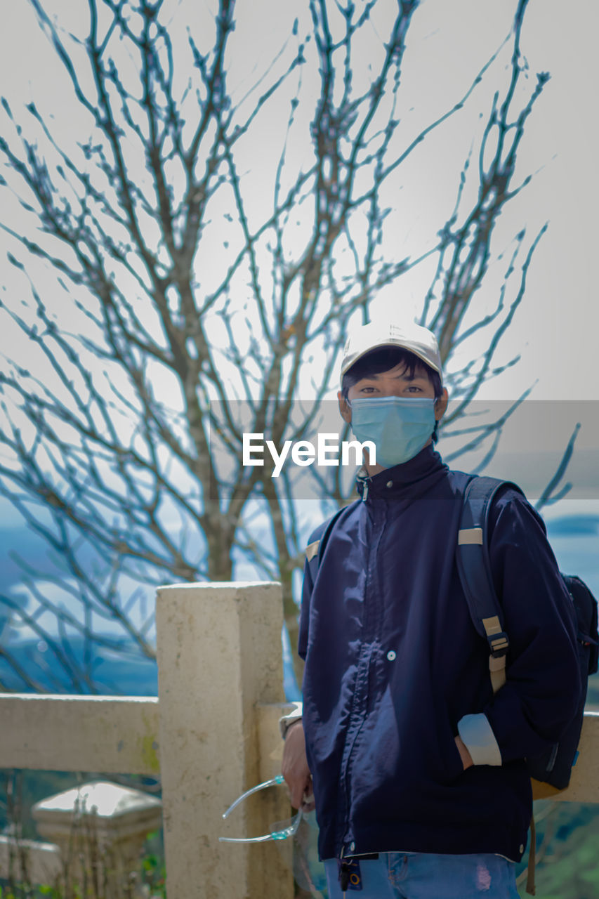Rear view of man standing against bare tree