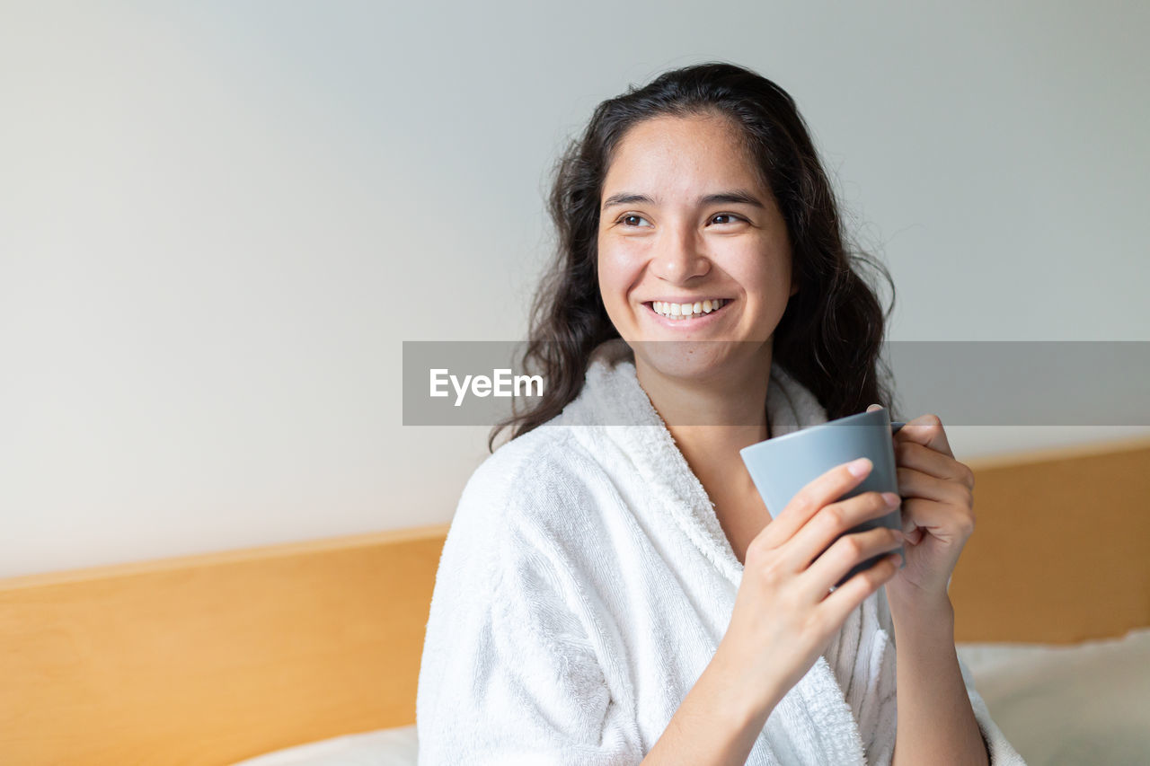 Young woman drinking coffee in bed in bathrobe