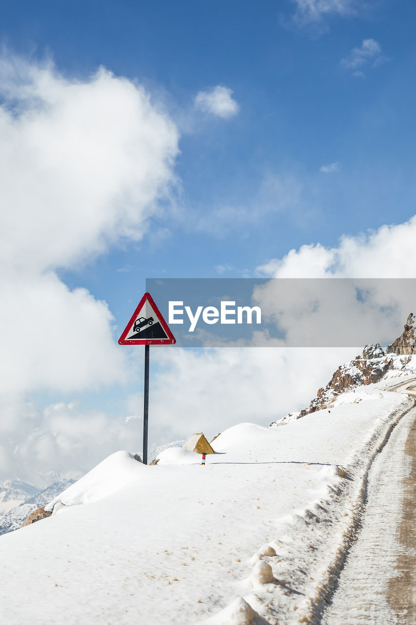 ROAD SIGN ON SNOW COVERED LANDSCAPE AGAINST SKY