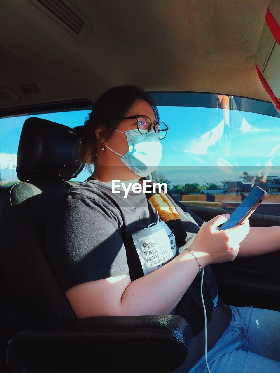 Young woman wearing mask driving car