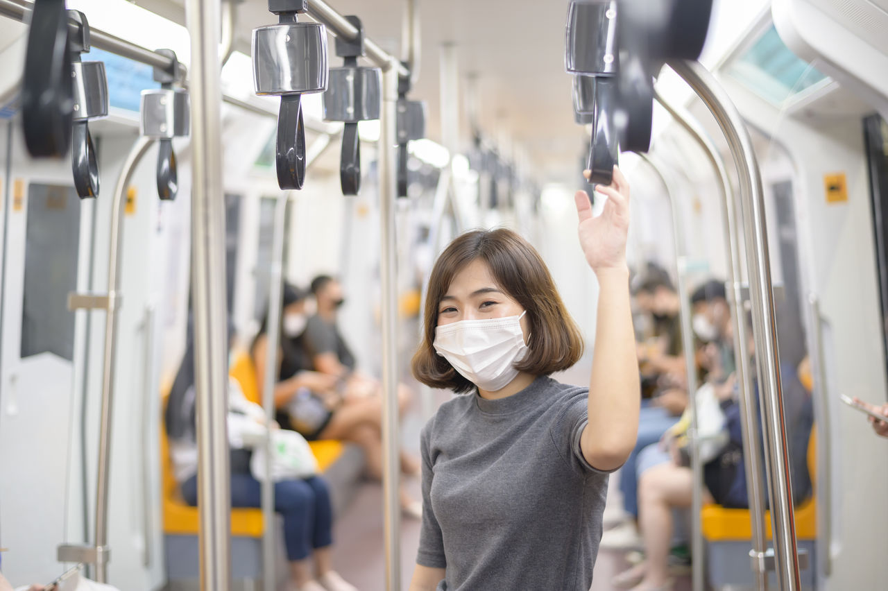 Portrait of young woman wearing mask standing in train
