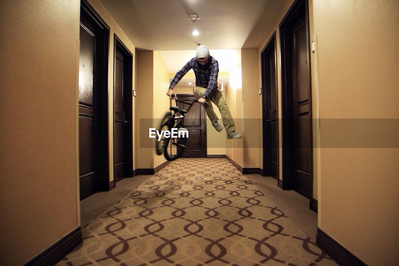 Man jumping mid-air on bmx bicycle in passageway
