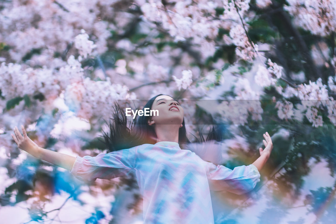 Young woman standing amidst flowering trees