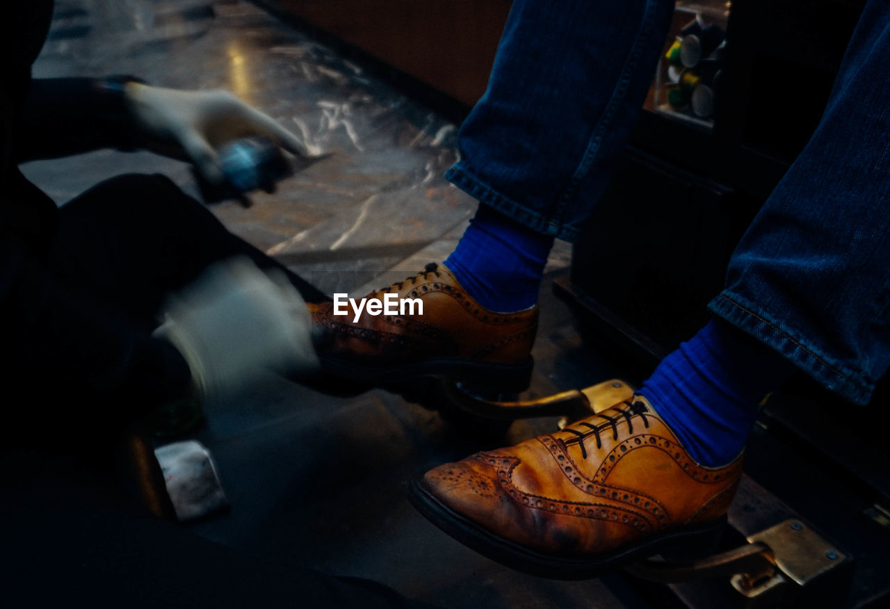 Blurred motion of shoeshiner polishing shoes of male customer