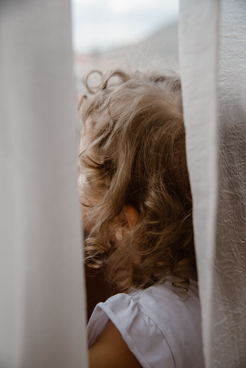 Closeup view of little girl behind the curtains