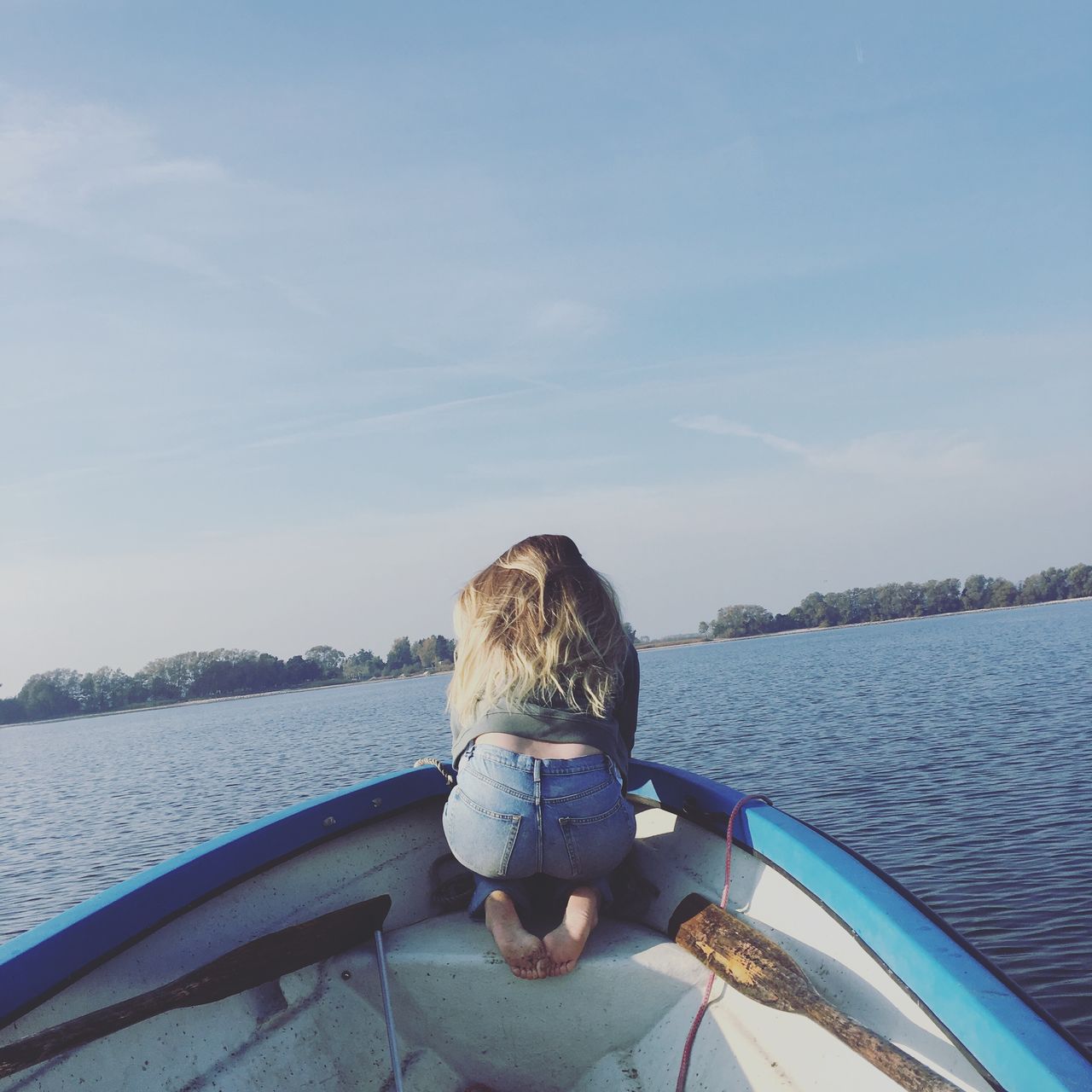 Rear view of woman kneeling in boat on river