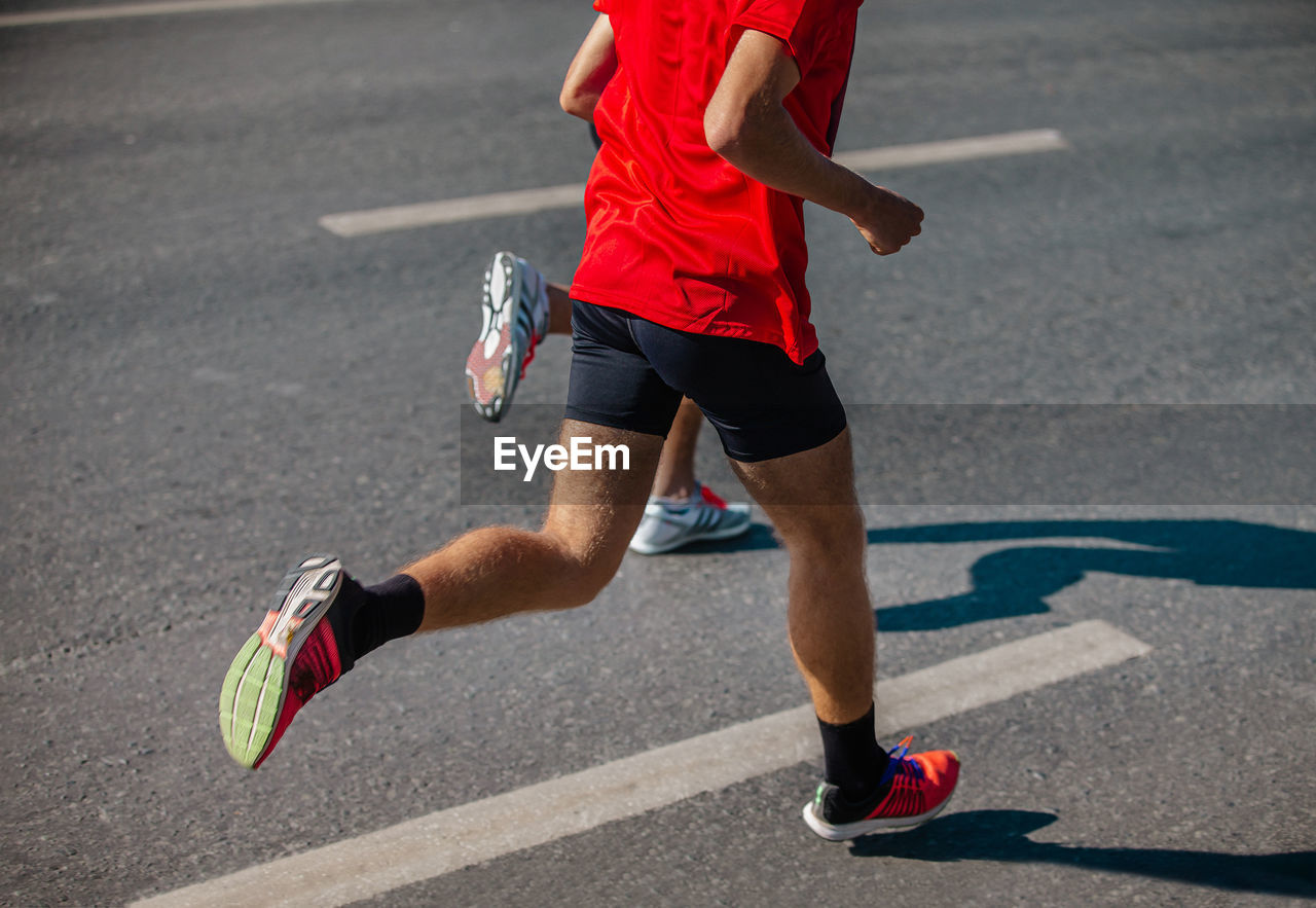 Male runner running marathon running on gray asphalt