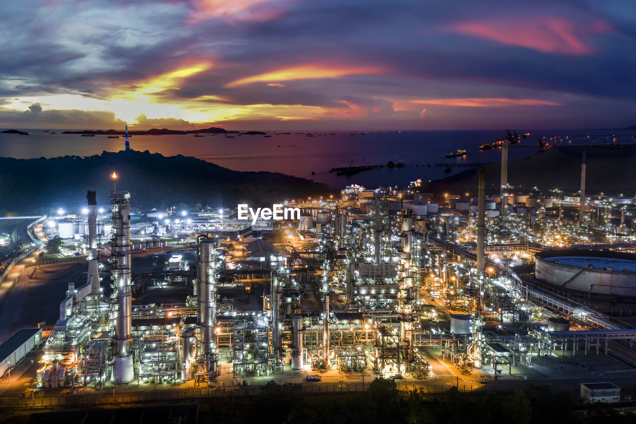 Oil refinery and petroleum industry factory zone at night over lighting with the sea 