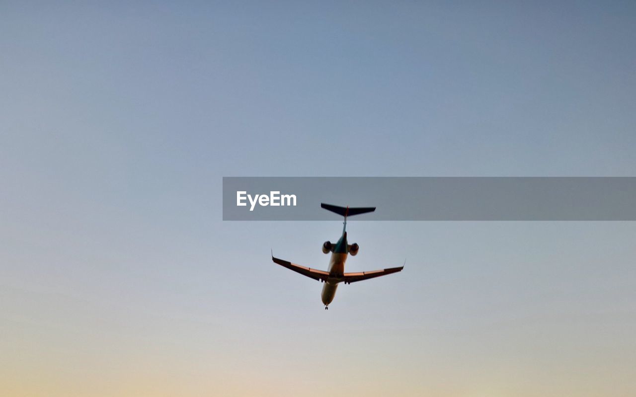 Low angle view of silhouette airplane against clear sky