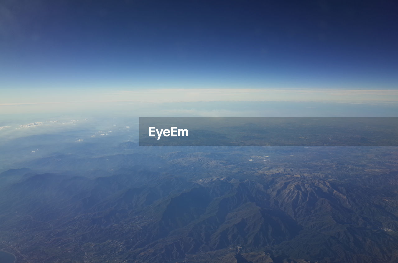 AERIAL VIEW OF MOUNTAINS AGAINST BLUE SKY